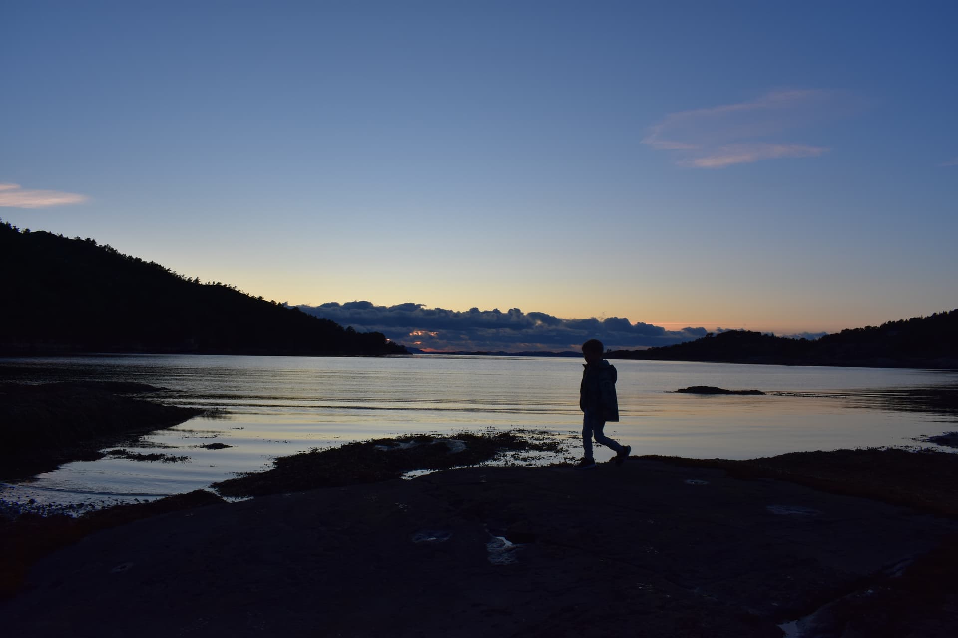 A child walking along the shore at sunset